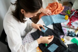 femme qui cout une pièce de tissus sur un jean