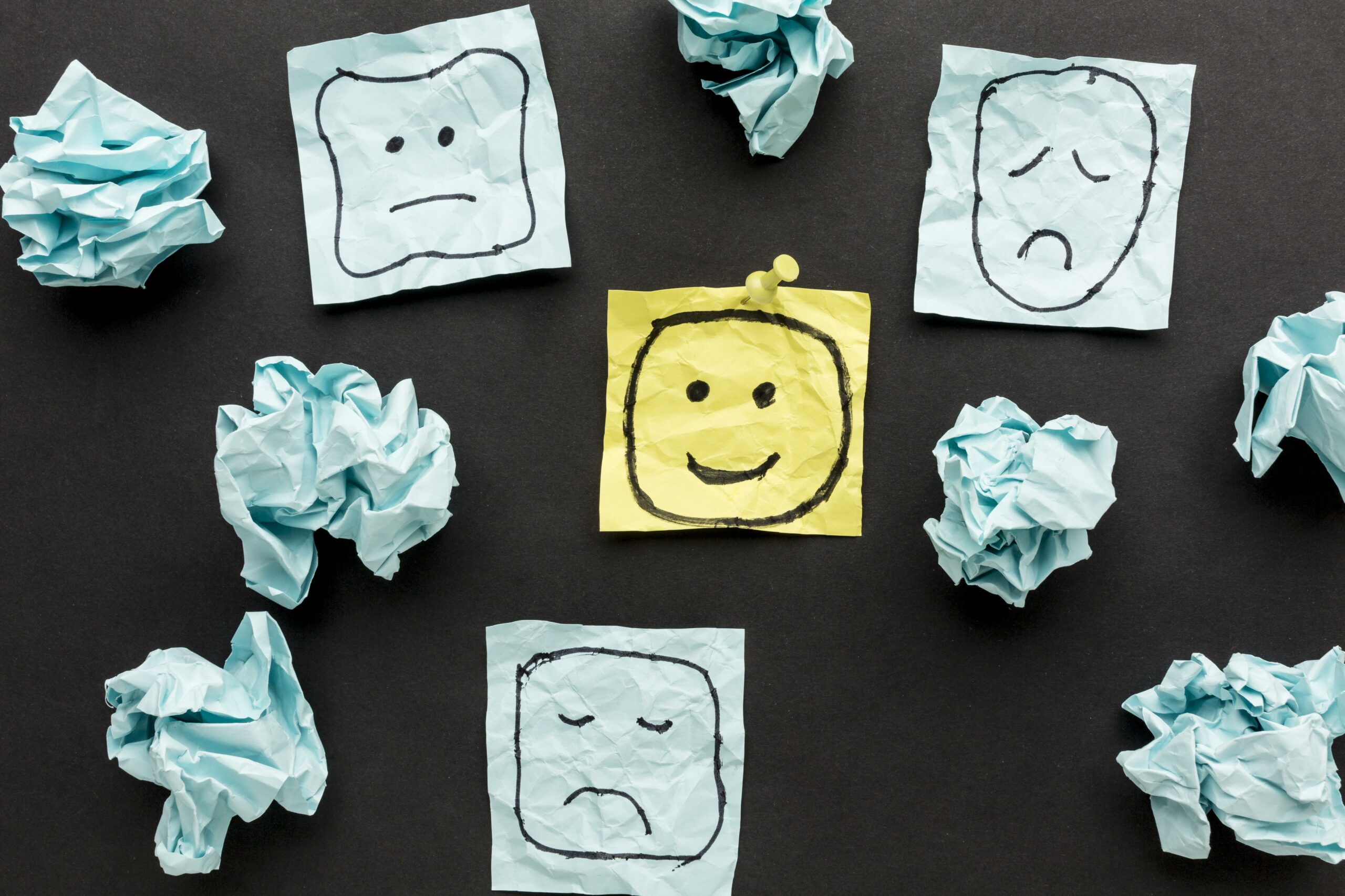 smiley rieur au milieu de smileys boudeurs