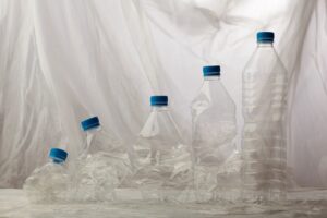 cinq bouteilles plastiques sont alignées, de la plus ecrasée à la plus propre