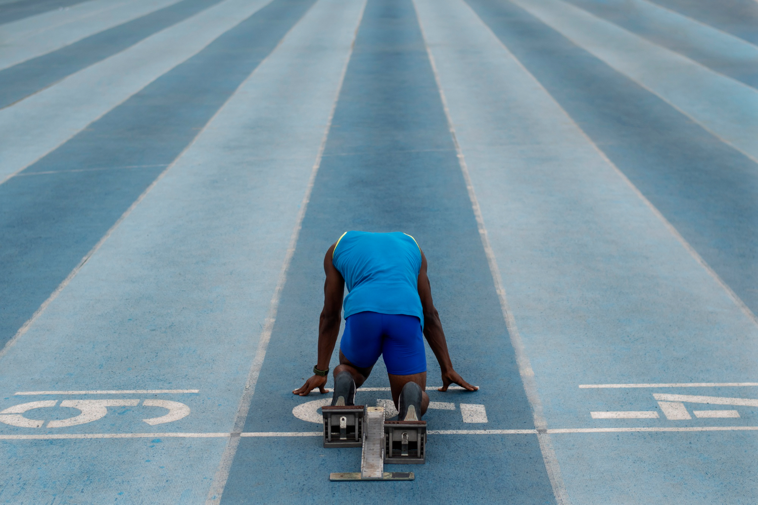 un athlète dans les starting-blocks va s'élancer sur la piste d'athlétisme