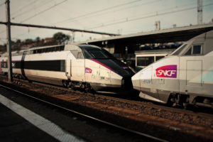 deux trains sncf se font face à quai avec un rayon de soleil